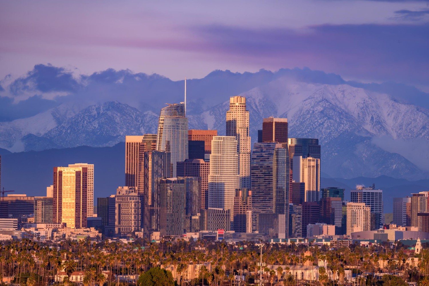 San Gabriel Valley Downtown los angeles skyline with snow capped mountains behind at sunset