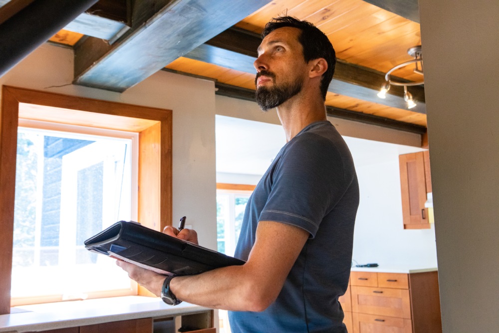 hoa-common-area-repair-responsibility-ceiling-leak Condo owner documenting a ceiling leak to determine HOA common area repair responsibility